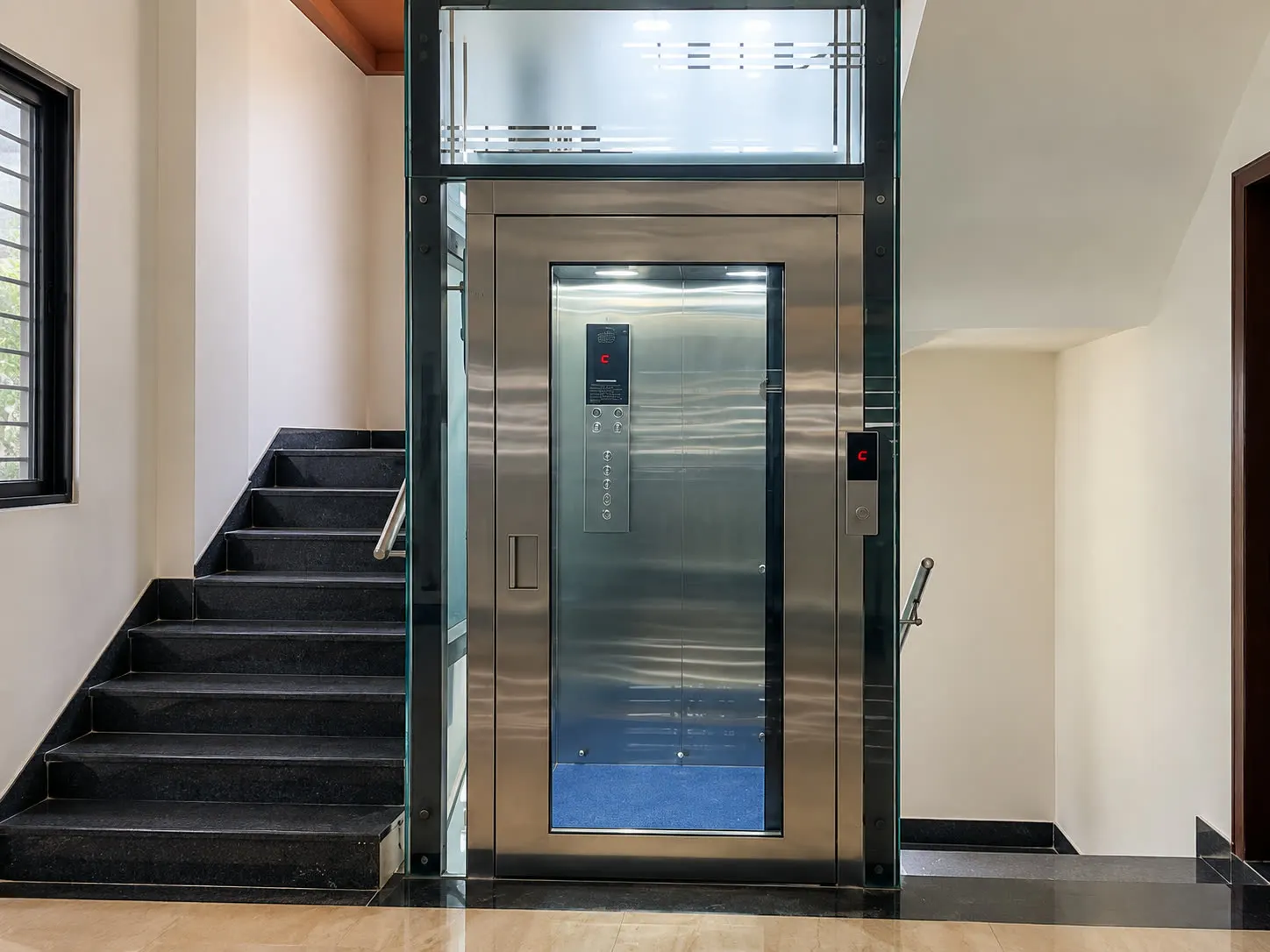 Glass enclosure home lift beside an indoor staircase