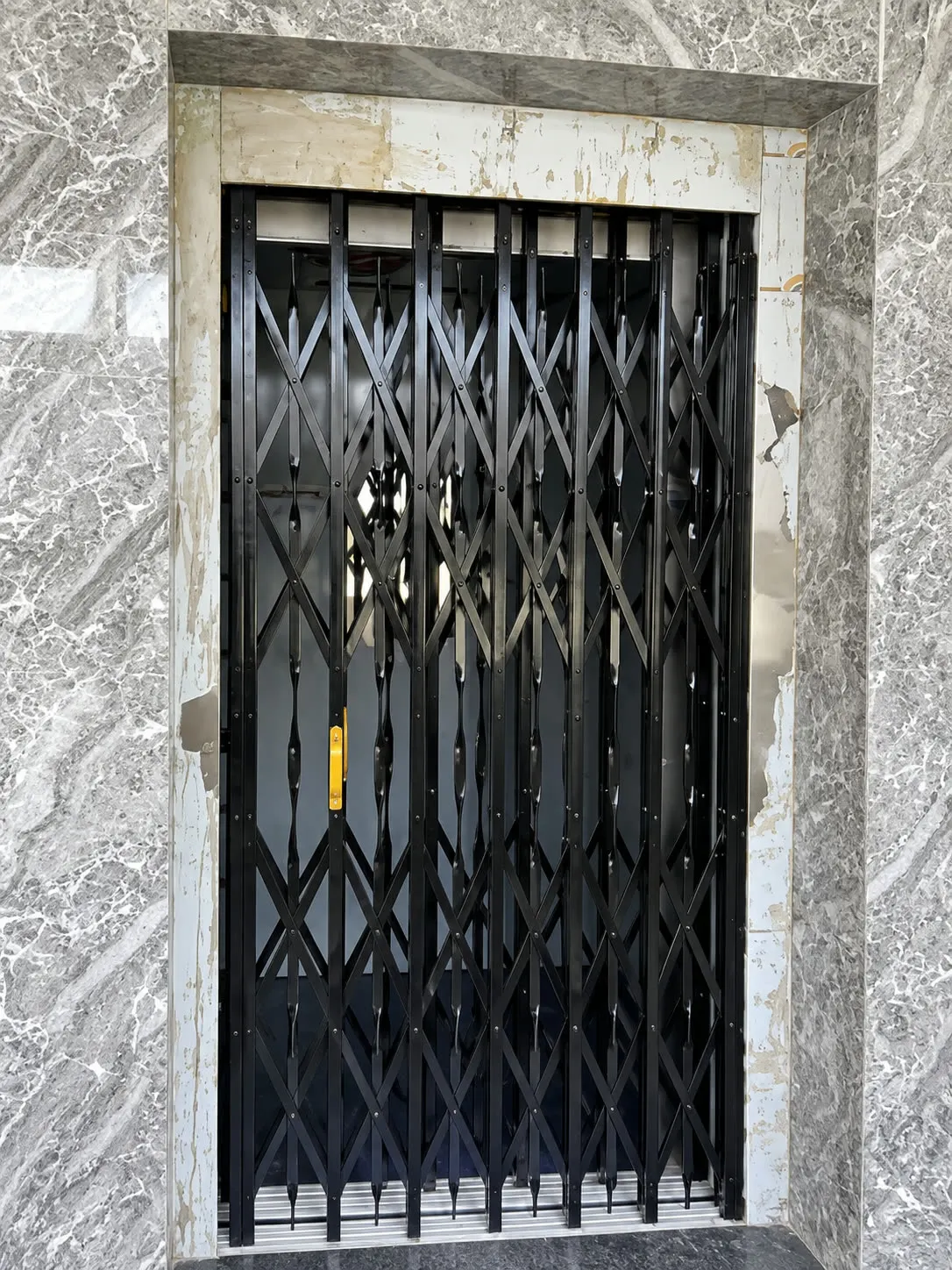 Home lift landing with a collapsible gate in a marble surround
